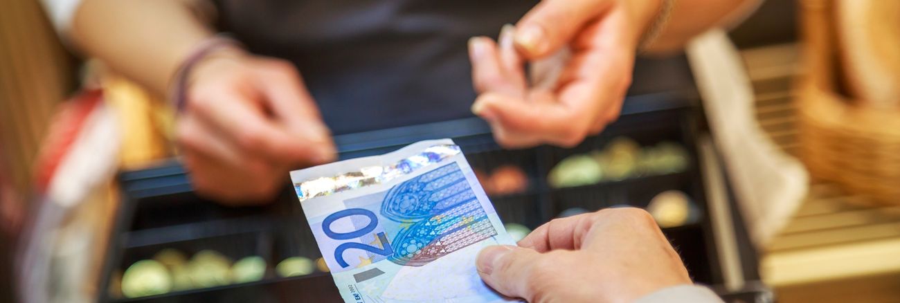 Eine Kundin reicht einer Kassiererin einen Zwanzig-Euro-Schein © iStock/pixinoo