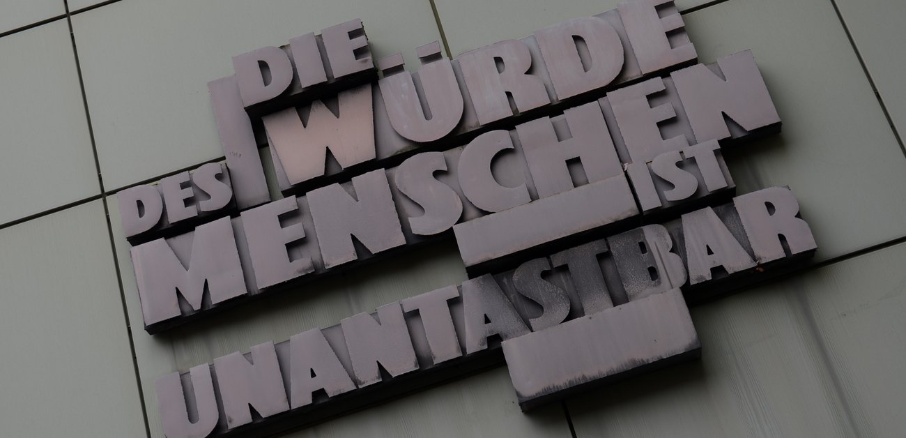 Das Grundgesetz-Zitat "Die Würde des Menschen ist unantastbar" an der Fassade eines Gerichtsgebäudes in Frankfurt am Main  © Arne Dedert/dpa