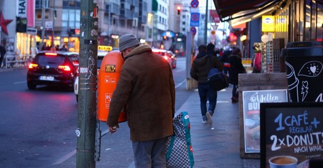 Ein Mann mit einer Plastiktüte sucht in einem Mülleiner nach Pfandflaschen © Wolfram Steinberg/dpa