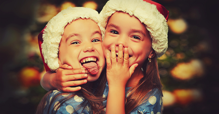 Lachende Kinder mit Weihnachtsmannmützen umarmen einander.  Foto: © istock.com/evgenyatamanenko