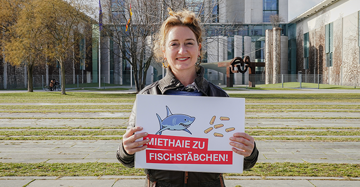Caren Lay vor dem Kanzleramt mit Schild: Miethaie zu Fischstäbchen