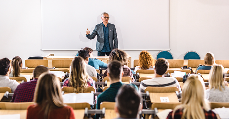 Studenten sitzen in einem Hörsaal vor einem Dozenten 