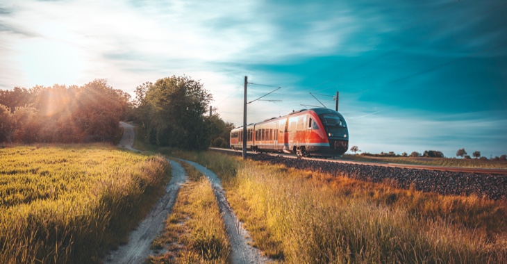 Ein Feldweg neben einem Bahngleis mit einem Regionalexpress der Bahn © iStock/Say-Cheese