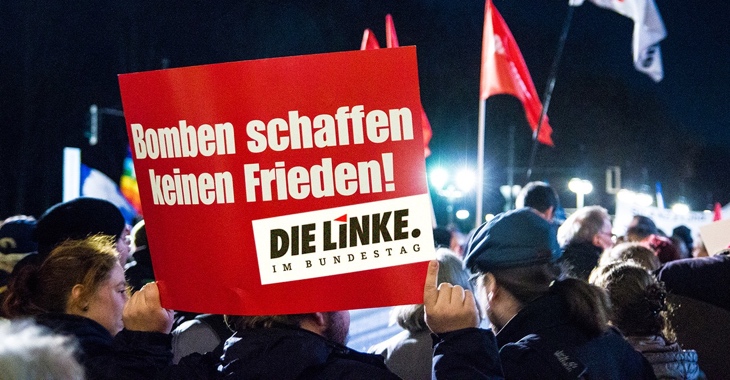 Teilnehmer an einer Friedenskundgebung halten ein Schild mit Aufschrift: Bomben schaffen keinen Frieden! Teilnehmer an einer Friedenskundgebung halten ein Schild mit Aufschrift: Bomben schaffen keinen Frieden!