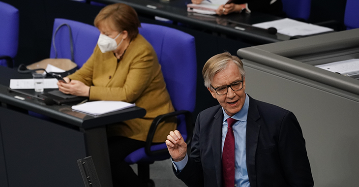 Dietmar Bartsch im Plenum mit Angela Merkel im Hintergrund