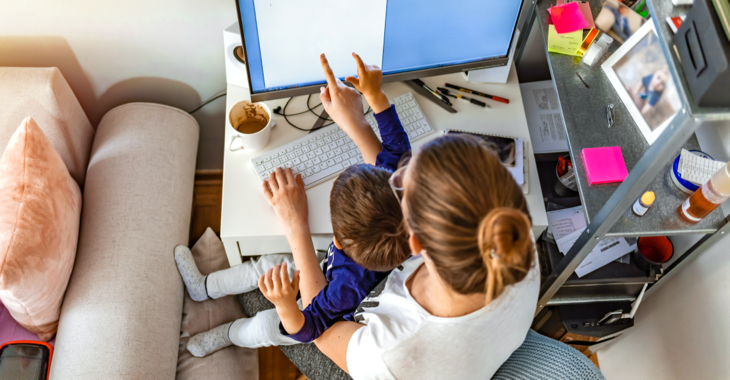 Eine Frau mit einem Kind auf dem Schoß zeigt auf einen Computerbildschirm © iStock/ljubaphoto