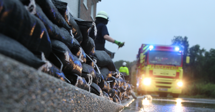 Einsatzkräfte der Feuerwehr errichten am Straßenrand eine Wassersperre aus Sandsäcken © picture alliance/Flashpic/Jens Krick