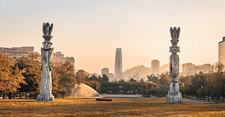 Traditionelle Statuen des indigenen Stammes Mapuche mit Skyline von Santiago, Chile, im Hintergrund @istock/diegograndi Traditionelle Statuen des indigenen Stammes Mapuche mit Skyline von Santiago, Chile, im Hintergrund