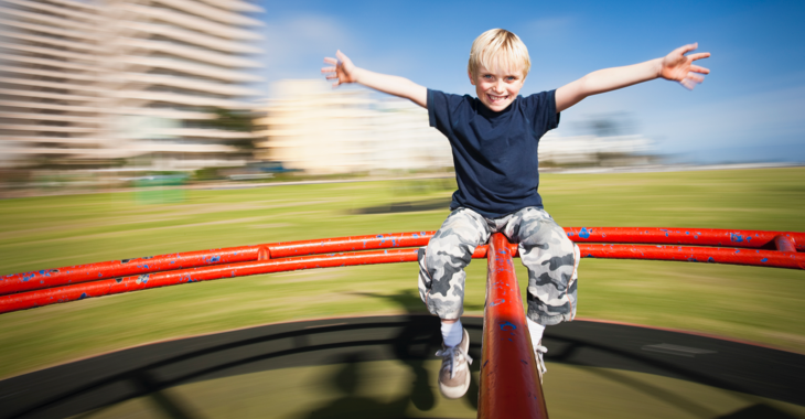 Ein Junge auf einem Karussell mit verschwommenen Wohnhochhäusern im Hintergrund © iStock/RapidEye Ein Junge auf einem Karussell mit verschwommenen Wohnhochhäusern im Hintergrund © iStock/RapidEye
