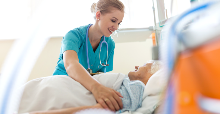 Eine Krankenschwester versorgt in einem Krankenhaus eine ältere Patientin, die im Bett liegt © iStock/PIKSEL