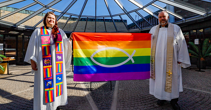 Zwei Priester der schwedischen Kirche posieren mit einer LGTBQ-Flagge, um die Vielfalt innerhalb der Kirche zu fördern