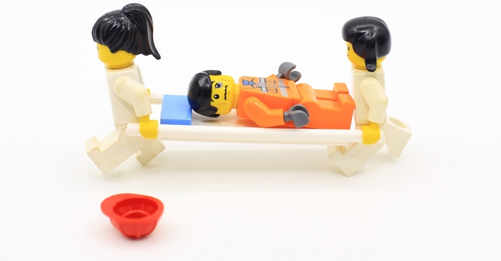 Lego-Figuren: Zwei Sanitäter tragen einen Patienten auf einer Trage © iStockphoto.com/LewisTsePuiLung