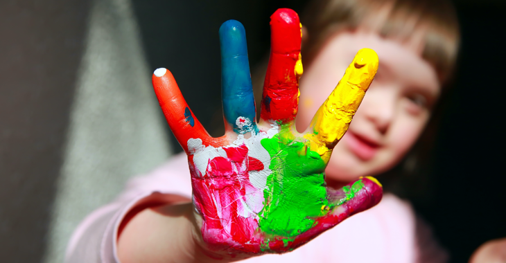 Mädchen mit Down-Syndrom hält ihre rechte Hand voller Farbe in die Kamera Mädchen mit Down-Syndrom hält ihre rechte Hand voller Farbe in die Kamera