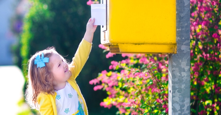 Ein kleines Mädchen steckt mit ausgestrecktem Arm einen Brief in einen Briefkasten © iStock/FamVeld