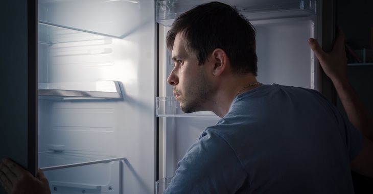 Ein Mann schaut in ein einen leeren Kühlschrank © iStock/vchal