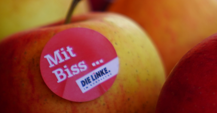 Ein Aufkleber auf einem Apfel mit der Aufschrift: Mit Biss... Fraktion DIE LINKE. im Bundestag