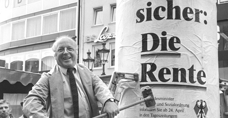 Norbert Blüm am 21. April 1986 mit einem Besen an einer Litfaßsäule mit dem Plakat »Denn eins ist sicher: Die Rente« © picture alliance/Peter Popp Norbert Blüm am 21. April 1986 mit einem Besen an einer Litfaßsäule mit dem Plakat »Denn eins ist sicher: Die Rente« © picture alliance/Peter Popp
