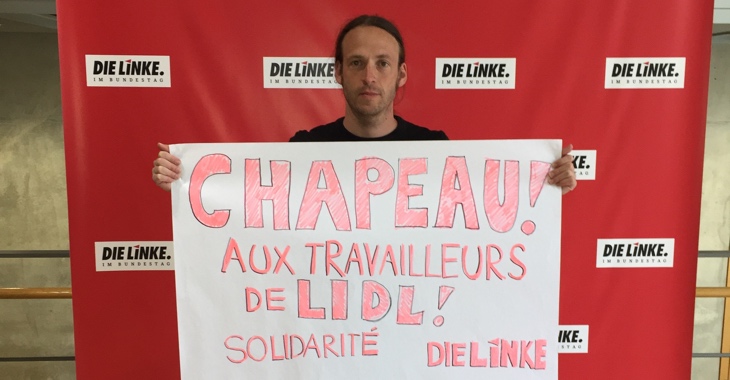 Pascal Maiser hält ein Transparent mit der Aufschrift: Chapeau aux travailleurs de Lidl! Pascal Maiser hält ein Transparent mit der Aufschrift: Chapeau aux travailleurs de Lidl!