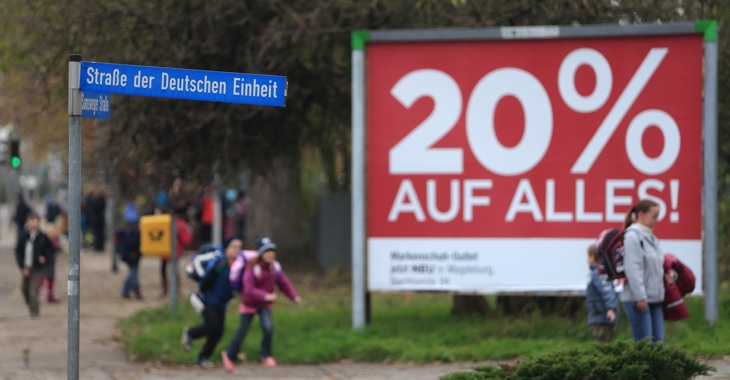 Passanten laufen in Wolmirstedt (Sachsen-Anhalt) an einem Straßenschild mit der Aufschrift »Straße der deutschen Einheit« vorbei © dpa