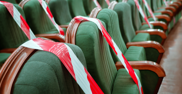 Leere grüne Theatersitzer mit rot-weißem-Absperrband © iStock/Standart