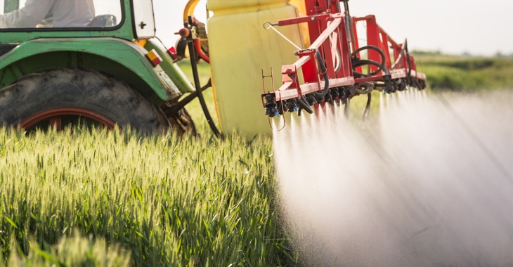 Ein Traktor versprüht Unkrautvernichtungsmittel auf einem Getreidefeld © iStockphoto.com/fotokostic