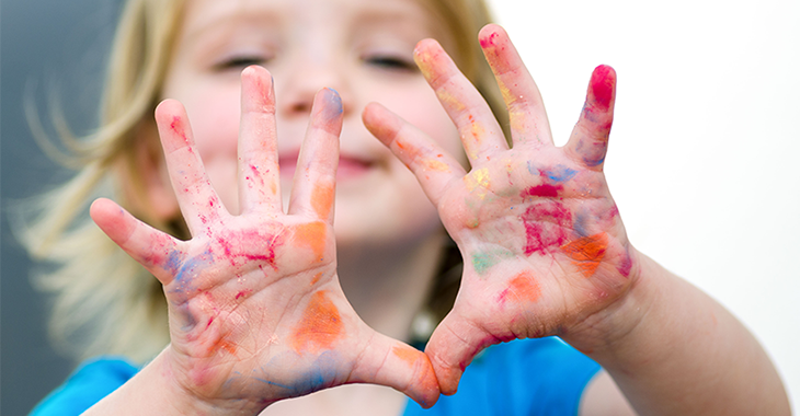 Ein Kind hält zehn mit Farbe bekleckste Finger seiner beiden Hände hoch | Foto: istockphoto.com/Elecstasy