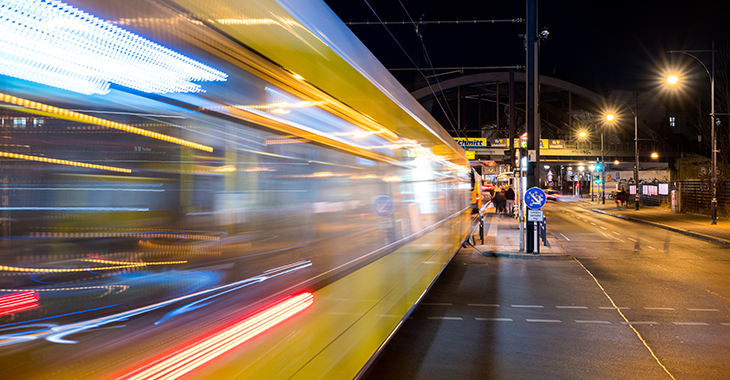 Eine gelbe Straßenbahn fährt nachts in eine Haltestelle ein, die von Straßenlaternen erleuchtet wird. Im Hintergrund ist eine Bahnbrücke zu sehen. Foto: © istock.com/holgs Eine gelbe Straßenbahn fährt nachts in eine Haltestelle ein, die von Straßenlaternen erleuchtet wird. Im Hintergrund ist eine Bahnbrücke zu sehen. Foto: © istock.com/holgs