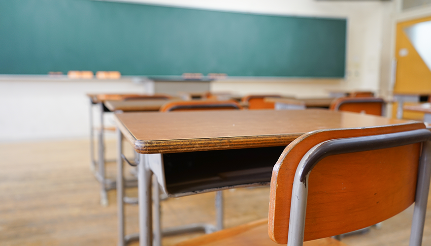 Ein leerer Klassenraum einer Schule mit einer sauberen Tafel, Pulten und abgenutzten Stühlen. Foto: © istock.com/maroke 