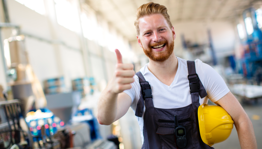 Ein Arbeiter mit gelbem Helm unter seinem linken Arm hebt zustimmend den rechten Daumen © iStock/milanvirijevic