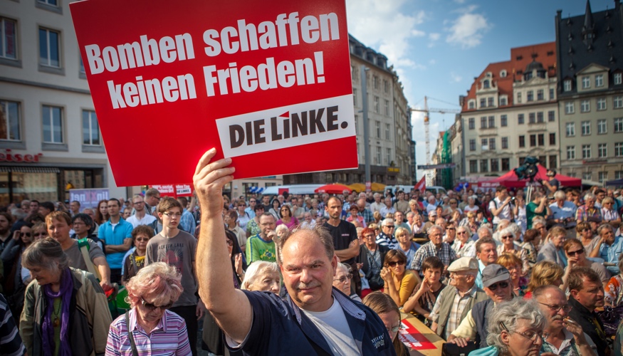 Bei einer Kundgebung in Leipzi hält ein Mann ein Schild mit der Aufschrift »Bomben schaffen keinen Frieden! DIE LINKE« © Jakob Huber