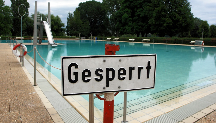 Vor einem Schwimmbecken eines Freibades steht ein Schild mit der Aufschrift Gesperrt © picture alliance/JOKER