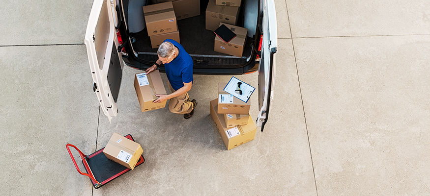 Pakete werden bei einer Lieferung von einem Kurierzusteller in ein Auto geladen. | Foto: © istock.com/Ridofranz